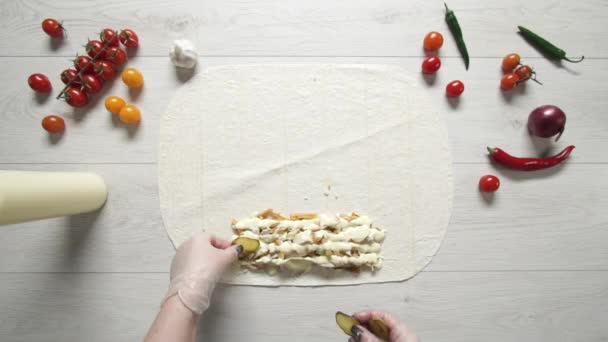Pandangan atas tangan koki dalam sarung tangan putih menempatkan acar pada doner kebab shawarma dalam pita atau lavash. Memasak shawarma dengan ayam, kentang goreng, keju dan sayuran — Stok Video