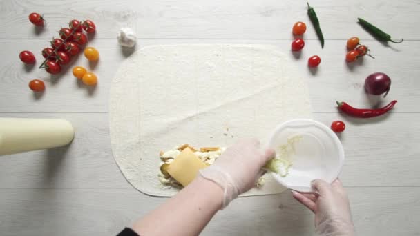 白い手袋でシェフの手のトップビューは、ピタやラバッシュでドナーケバブショールマルチにキャベツを置きます。鶏肉、フライドポテト、チーズ、野菜とシャワルマを調理します — ストック動画