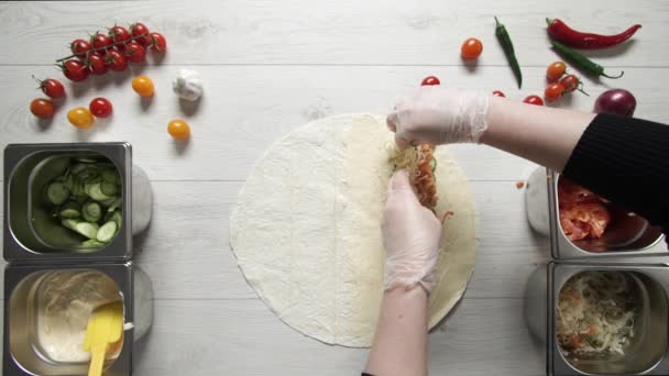 Le mani di chef in guanti bianchi mettono cavoli a doner kebab shawarma in pita o lavash. Shawarma da cucina con pollo, patatine fritte, formaggio e verdure — Video Stock