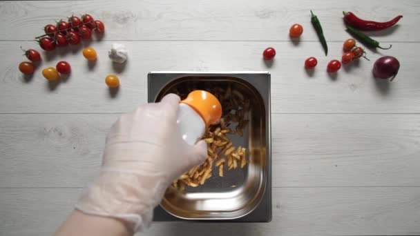 Šéfkuchař v rukavicích dává sůl na horké a lahodné hranolky — Stock video