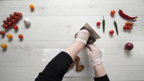Szef kuchni umieszcza chrupiące skrzydełka kurczaka i nogi w papierowej torbie — Wideo stockowe