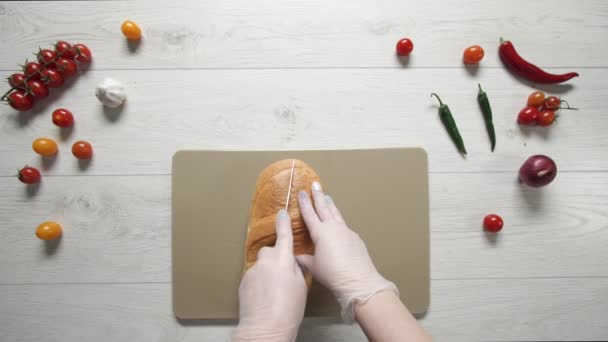 Draufsicht auf das Schneiden von frischem Brot auf einem Schneidebrett aus Kunststoff. — Stockvideo