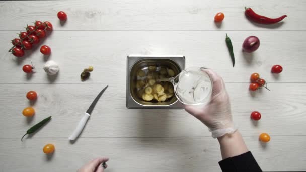 Chef gießt Wasser in Metallbehälter mit Gurkenscheibe — Stockvideo