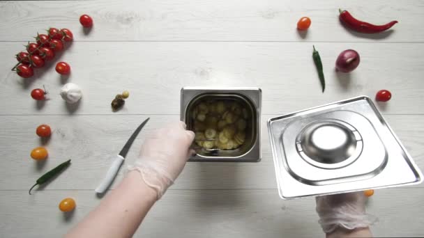 Chief neemt een paar plakjes augurken komkommers uit metalen container — Stockvideo