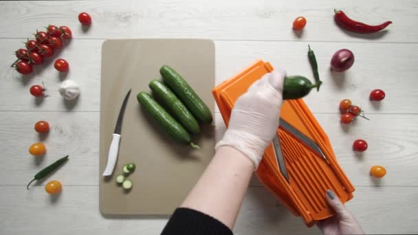 Шеф-кухар розрізає огірки на пластиковій решітці — стокове відео