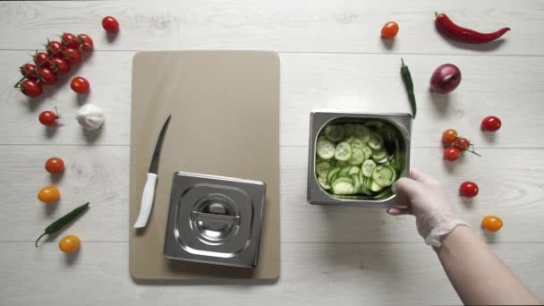 Chef ferme le récipient en métal avec des concombres coupés 