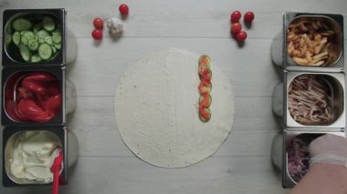 Şefin beyaz eldivenli en iyi görüntüsü, pide ya da lavda doner kebap shawarma 'nın üzerine soğan turşusu koyuyor. Tavuk, patates kızartması, peynir ve sebzeli shawarma.