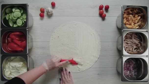 Top view of chef hands in white gloves puts souse on doner kebab shawarma in pita or lavash. shawarma with chicken, french fries, cheese and vegetable — Stock Video