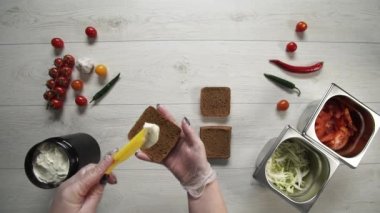 Profesyonel şefin en iyi görüntüsü fast food restoranında lezzetli bir hamburger pişirir. Eldivenli kadın aşçı hamburgerler için şiş ekmek koyuyor.