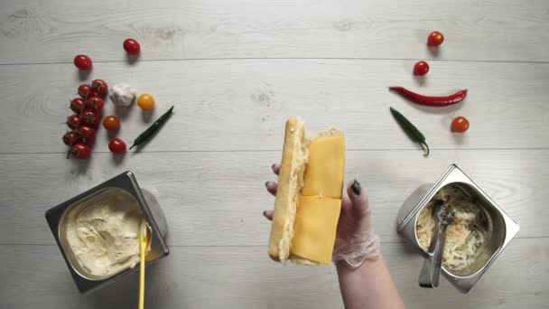 Vista superior de chef profesional cocina un delicioso sándwich en el restaurante de comida rápida. Cocinera en guantes pone carne de cerdo en sándwich — Vídeos de Stock