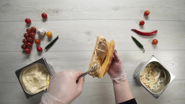 Profesyonel şef fast food restoranında lezzetli bir sandviç pişiriyor. Eldivenli kadın şef sandviçe domuz eti koyar. — Stok video