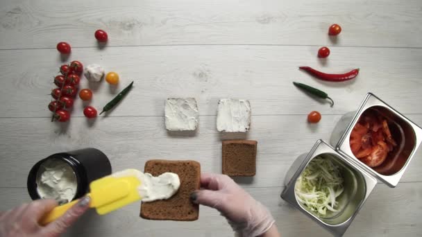 Vue de dessus du chef professionnel cuisine un délicieux hamburgers au restaurant de restauration rapide. Femme chef dans des gants met souse sur pain glacé pour hamburgers 