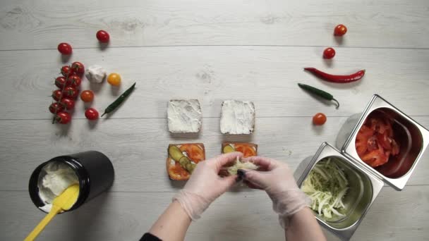 Vue de dessus du chef professionnel cuisine un délicieux hamburgers au restaurant de restauration rapide. Femme chef dans des gants met le chou dans des hamburgers 