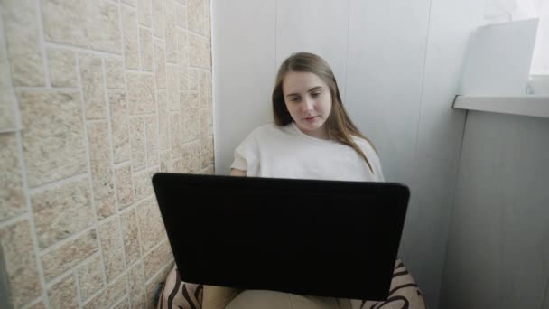 Χαμογελαστή νεαρή γυναίκα χρησιμοποιώντας φορητό υπολογιστή κοιτάζοντας το μήνυμα δακτυλογράφησης οθόνης — Αρχείο Βίντεο