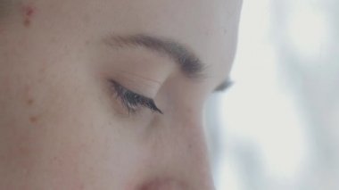 Dişi bir kadının gözünün aşırı yakın çekimi. Genç bayan evde çalışıyor.