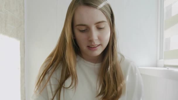 Dizüstü bilgisayar kullanarak gülümseyen genç bir kadın ekran daktilo mesajına bakıyor — Stok video