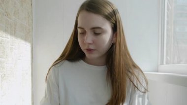 Genç bir kadın akıllı telefon ekranına bakıyor ve Coronavirus 'un kendini izolasyonundan dolayı bilgisayarla evden çalışıyor. Otantik ev işyeri. El kamerasıyla, el kamerasıyla. Coronavirüs salgını 2020.