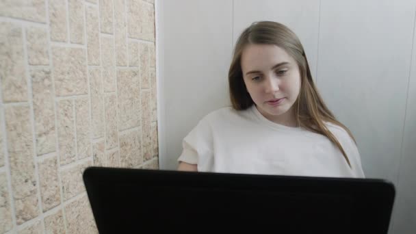 Dizüstü bilgisayar kullanarak gülümseyen genç bir kadın ekran daktilo mesajına bakıyor — Stok video