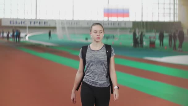 Jonge vrouwelijke loper komt naar sport arena en zwaaien hand naar haar vrienden — Stockvideo