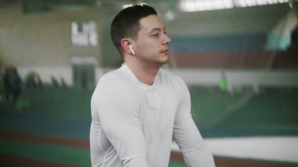 Jonge atleet man met draadloze hoofdtelefoon opwarmen voor sport oefening — Stockvideo