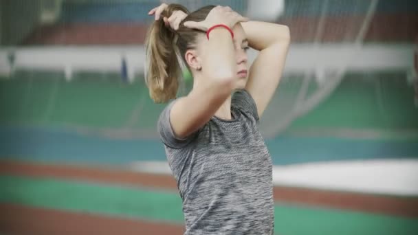 운동을 하기 전에 머리를 모으는 젊은 운동 여자 — 비디오