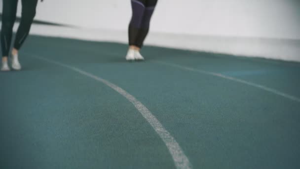 Dois jovens atletas do sexo feminino com sapatos de pista Spike Key Spike Key fica na posição de início baixo e corre — Vídeo de Stock