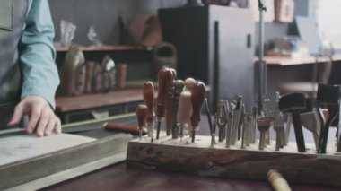 Tanner deri ile çalışmak için bir alet seçiyor. El yapımı için çok farklı araçlar. Metal araçlar