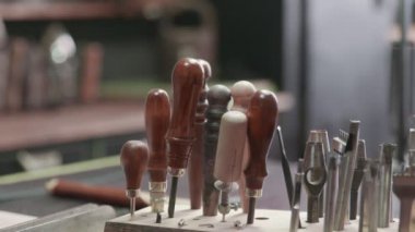 Tanner deri ile çalışmak için bir alet seçiyor. El yapımı için çok farklı araçlar. Metal araçlar