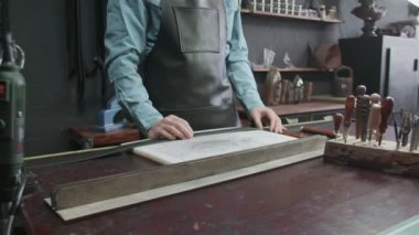 Tanner deri ile çalışmak için bir alet seçiyor. El yapımı için çok farklı araçlar. Metal araçlar