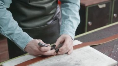 Tanner kemer için deri keser. Deri atölyedeki deri kemerin çalışma süreci. Adam el işi aleti tutuyor ve çalışıyor. Tanner eski tabakhanede..
