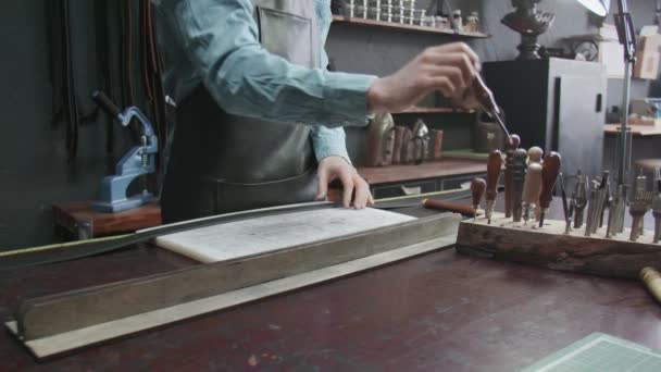 Der Gerber greift zu einem Werkzeug für die Arbeit mit Leder. Viele verschiedene Werkzeuge für die Handarbeit. Metallwerkzeuge — Stockvideo