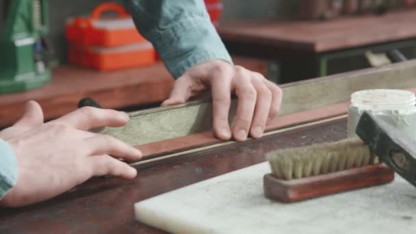Fechar-se do bronzeador profissional o homem põe a pasta em um cinto na oficina. Processo de trabalho da correia de couro na oficina de couro . — Vídeo de Stock