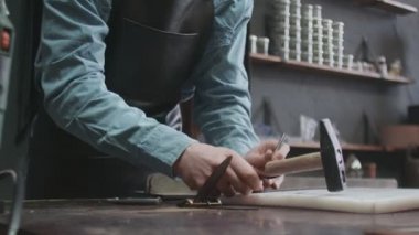 Profesyonel bronzlaştırıcı deri atölyesinde yeni kahverengi deri kemerde delikler açıyor. Deri atölyedeki deri kemerin çalışma süreci..