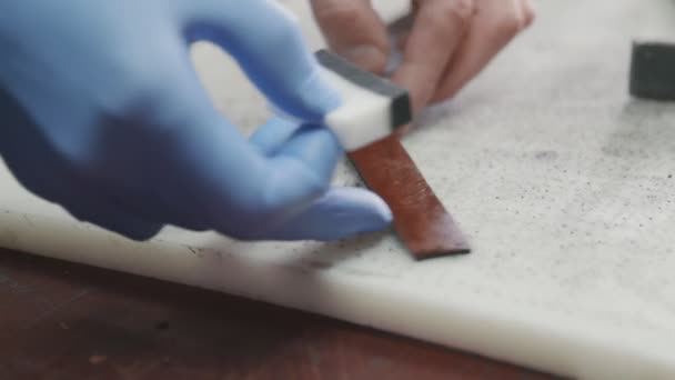 Aplicando tinte de borde negro al cuero. Proceso de trabajo del cinturón de cuero en el taller de cuero . — Vídeos de Stock