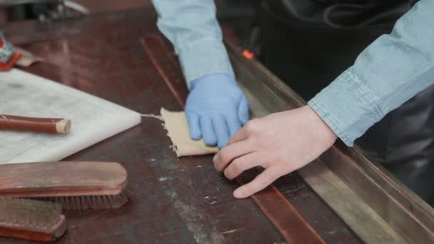 Le tanneur professionnel utilise un chiffon pour tapis une ceinture. Processus de travail de la ceinture en cuir dans l'atelier de cuir . — Video