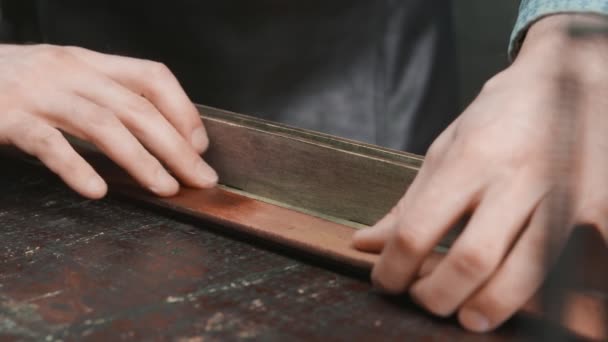 Il primo piano di conciatore professionale mette la pasta su una cintura in workshop. Processo di lavorazione della cintura in pelle nell'officina . — Video Stock