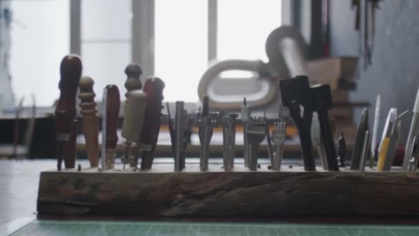 Narzędzia garbarskie w drewnianym stojaku. Proces pracy w warsztacie skórzanym. — Wideo stockowe