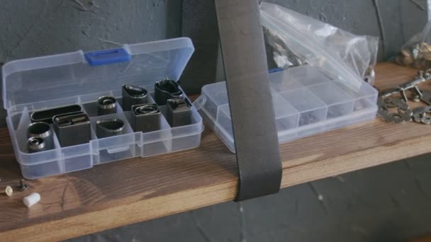 Accesorios de metalurgia para trabajar en cuero sobre un estante de madera. Proceso de trabajo en el taller de cuero . — Vídeo de stock