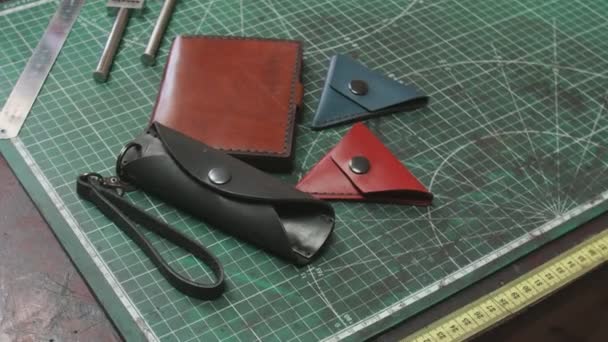 Finished handmade leather wallets keyholders on tanners table — Stock Video
