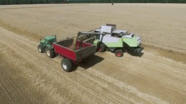 Buğday tarlasında çalışan hasat ve traktörün hava görüntüsü.