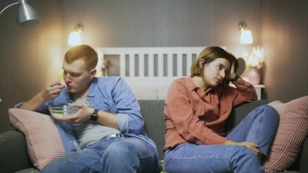 Quarreled man and woman sitting on the sofa and eating popcorn Video Clip