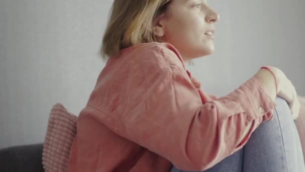 Scared woman sitting on the sofa and watching horror movie — Stock Video