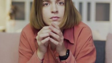 Genç bir kadın kanepede oturur ve televizyon izler. Kameraya bak.