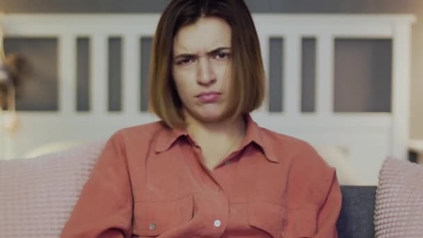 Young angry woman sitting on the sofa, eating popcorn and watching TV — Stock Video