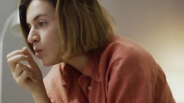 Genç hevesli kadın kanepede oturuyor, patlamış mısır yiyor ve televizyon seyrediyor.