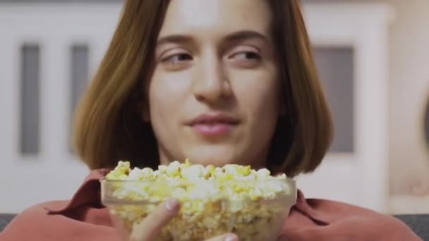 CLose up of young woman sitting on the sofa, eat popcorn, watching TV and falling alseep — Stok Video
