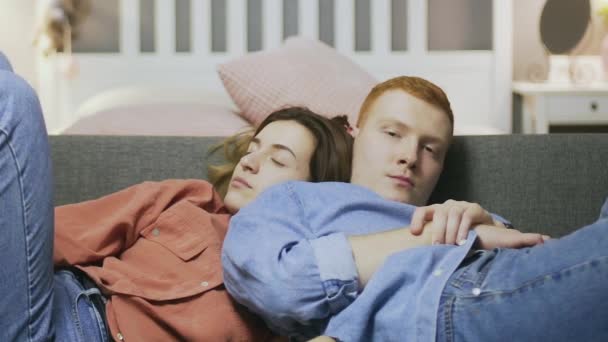 Spící mladý muž a žena sedí na pohovce a dívá se na televizi — Stock video