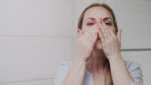 Mujer aplicando loción o aceite y mirando a la cámara — Vídeos de Stock