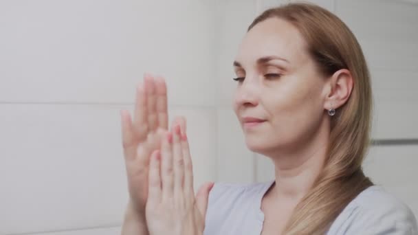 Volwassen vrouw die lotion of olie aanbrengt en in de spiegel kijkt — Stockvideo