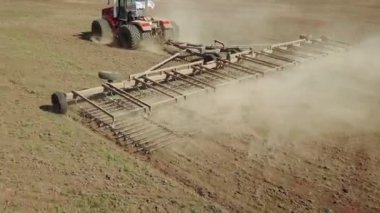 Büyük bir kanca kuvvetiyle enerji dolu güçlü bir traktörün hava görüntüsü, sonbaharda kış ekinleri için bir disk ekiciyle ekin ekiyor.